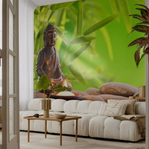 Fotomural Premium Sand - Una estatuilla de Buda con una vela encendida sobre un fondo de vegetación y piedras. - 100x70cm - La vida es bella - Decoración de pared moderna para salón y dormitorio ARTTOR