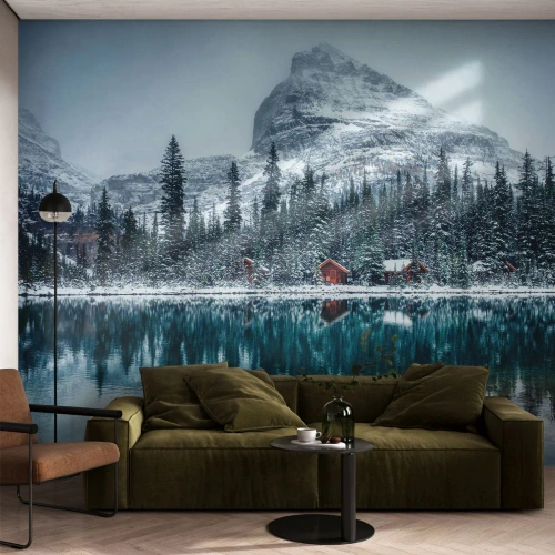 Fotomural Premium Sand - Un bosque cubierto de nieve y una cabaña de montaña junto a un lago turquesa. - 100x70cm - Retiro canadiense - Decoración de pared moderna para salón y dormitorio ARTTOR