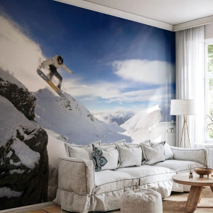 Fotomural Premium Canvas - Un snowboarder salta desde un acantilado con montañas cubiertas de nieve al fondo. - 100x70cm - Libertad sin fronteras - Decoración de pared moderna para salón y dormitorio ARTTOR