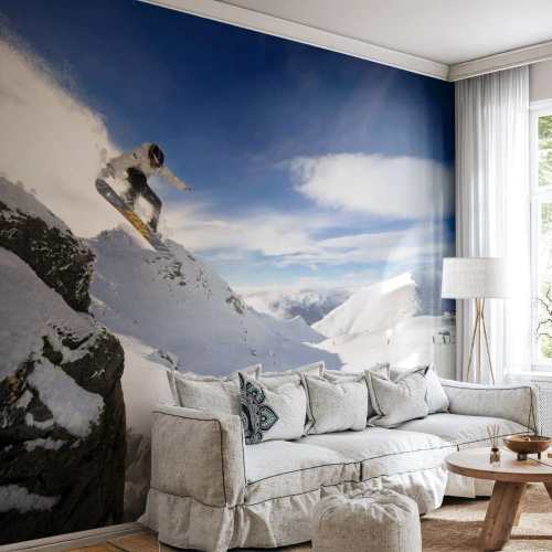 Fotomural Premium Sand - Un snowboarder salta desde un acantilado frente a un paisaje montañoso. - 100x70cm - Libertad sin fronteras - Decoración de pared moderna para salón y dormitorio ARTTOR