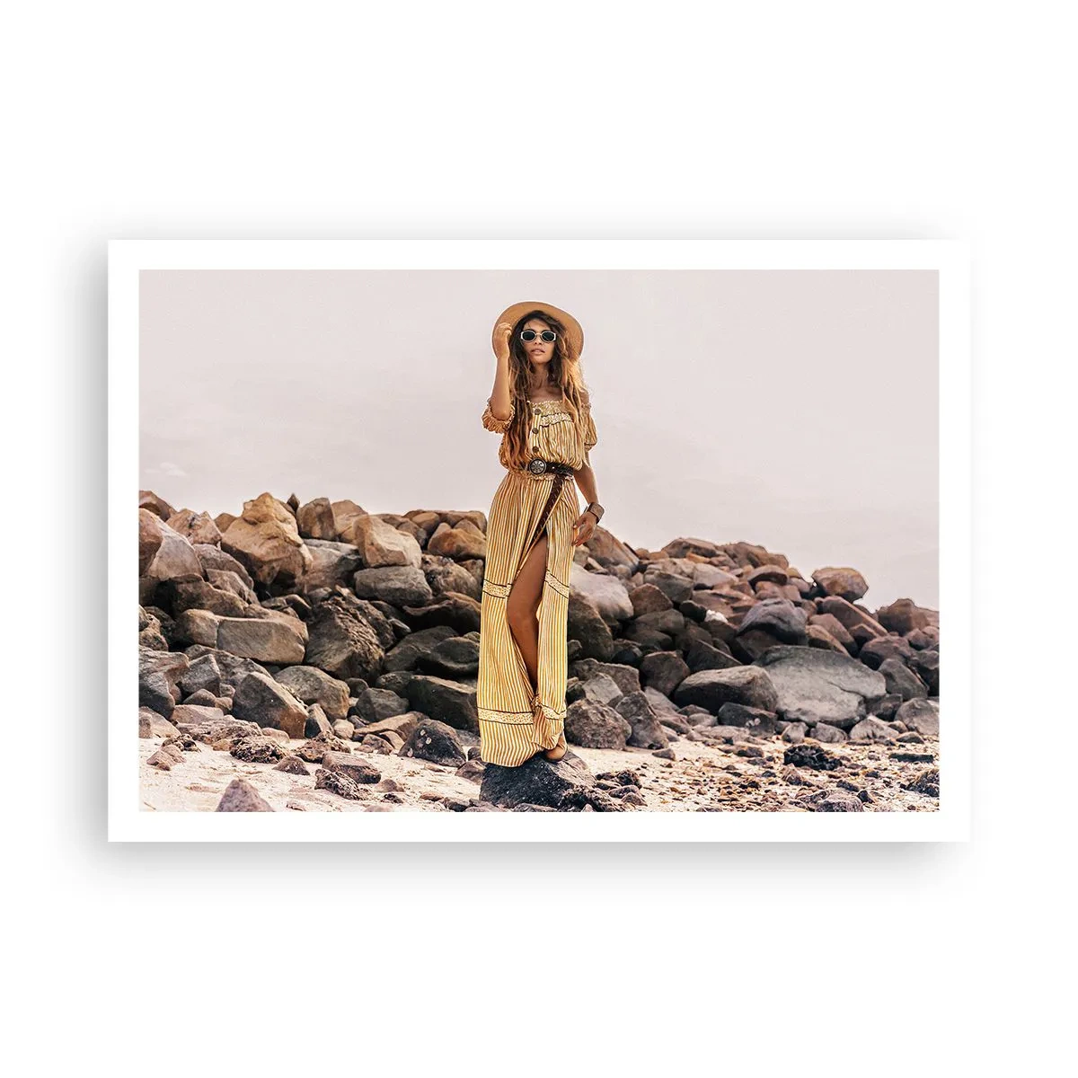 Póster - Una mujer con estilo boho sobre un fondo de playa rocosa. - 100x70cm - La magia de las piedras - Decoración de pared moderna para salón y dormitorio ARTTOR