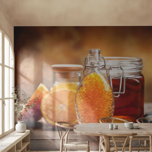 Fotomural Premium Sand - Una botella de aceite de naranja y un tarro de miel sobre madera. - 100x70cm - Sabores y aromas soleados - Decoración de pared moderna para salón y dormitorio ARTTOR