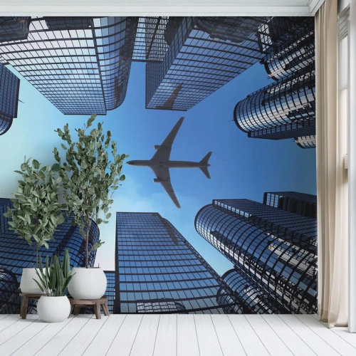 Fotomural Premium Sand - Rascacielos modernos y un avión volando en el cielo. - 100x70cm - La vista desde el abismo de cristal - Decoración de pared moderna para salón y dormitorio ARTTOR